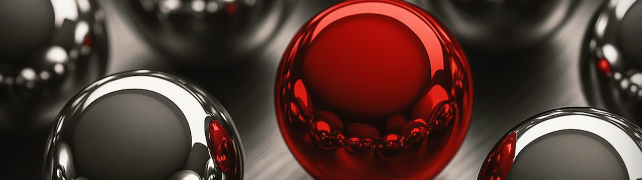 چند کره نقره‌ای سه‌بعدی و یک کره قرمز درخشان در مرکز تصویر، نماد خلاقانه تمایز بصری و جلب نگاه