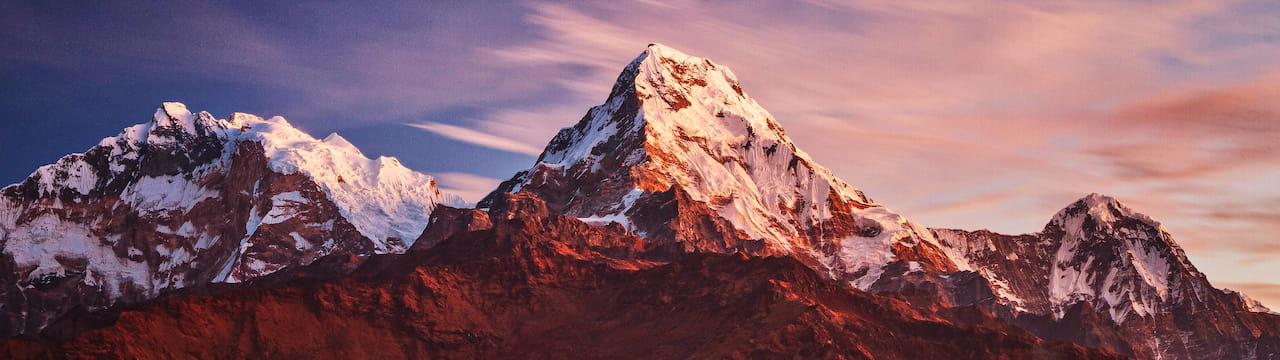 والپیپر کوهستان سرخ برفی در میان ابرها و زیر آسمان آبی با کیفیت UHD (4k)